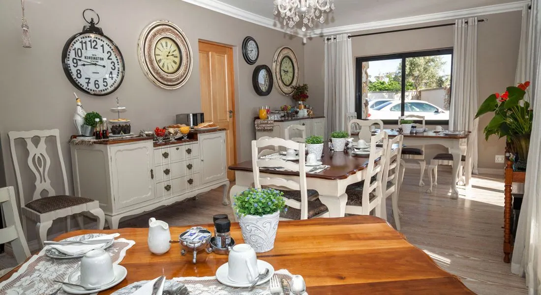 Dining area with wooden tables white chairs and wall clocks in a bright room