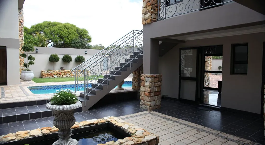 Modern patio with pool staircase and stone fountain in a courtyard setting