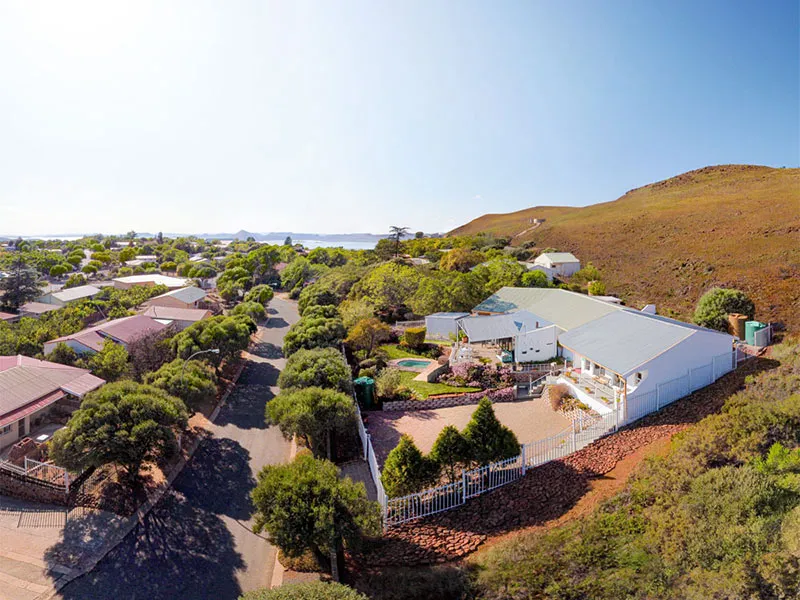 Aerial view of suburban houses with gardens and a hilly landscape