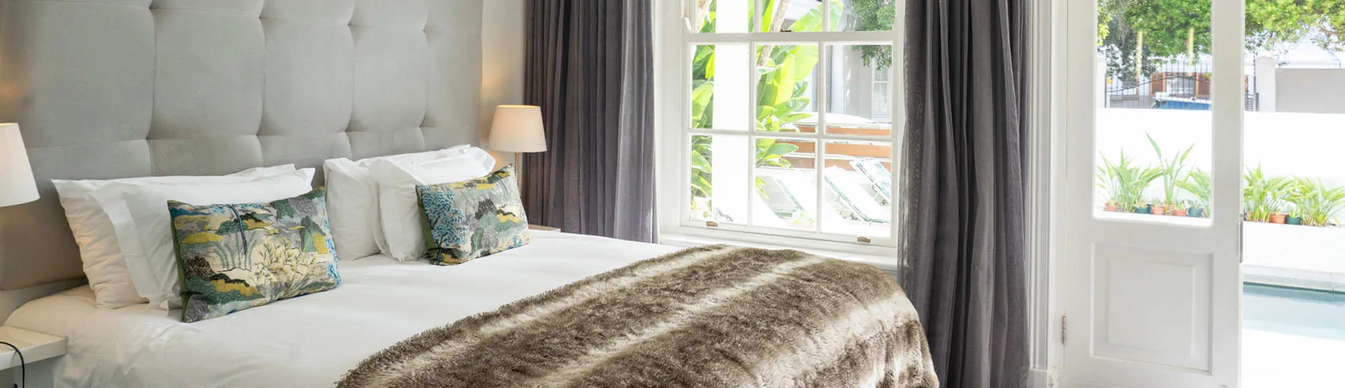 Cozy bedroom with a large bed pillows and an open door to a garden