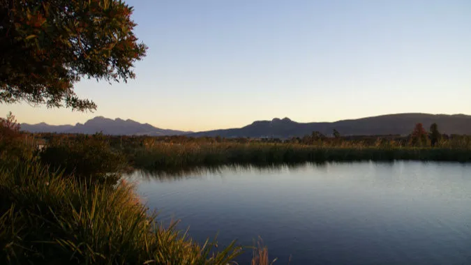 Tranquil pond with mountains in the background at sunset