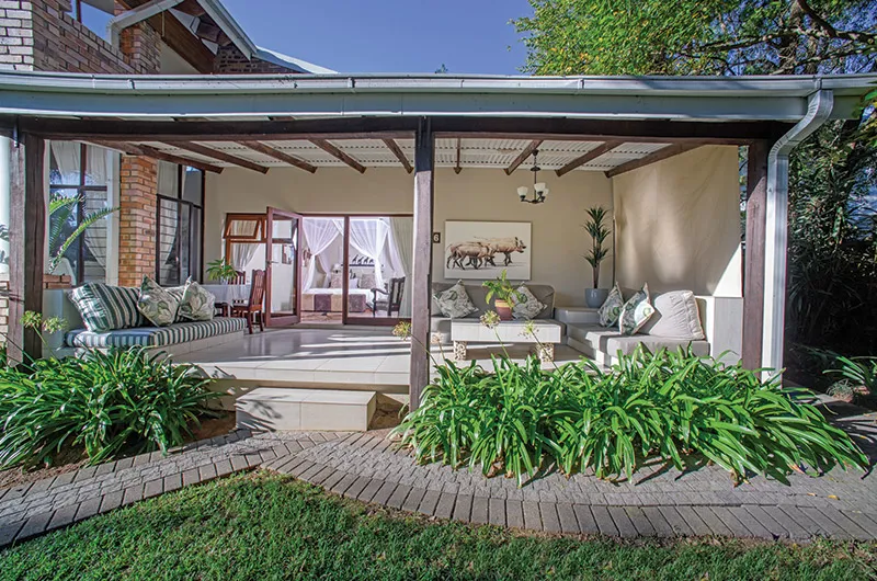 Covered patio with seating area plants and view into a living room