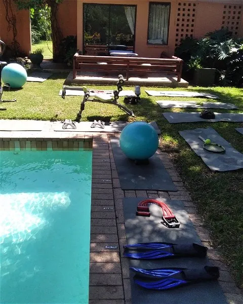 Outdoor exercise area with pool yoga mats and fitness equipment on grass