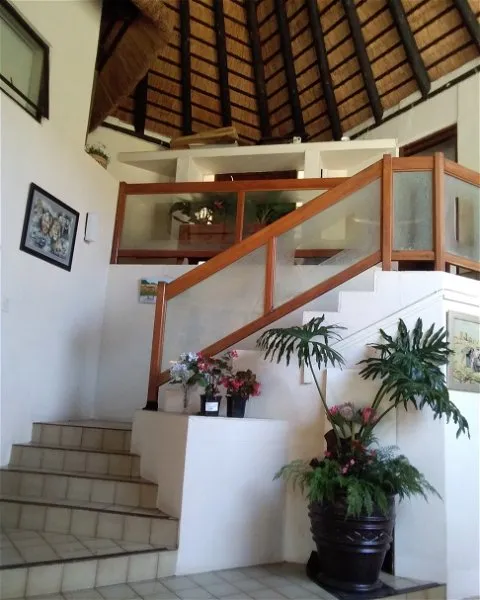 Indoor staircase with plants and flowers high ceiling and wooden railing