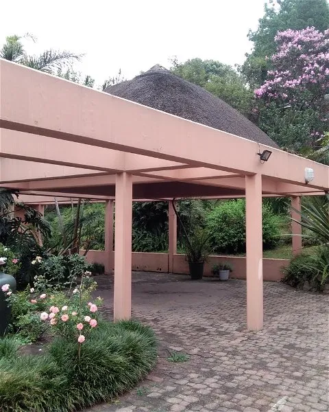 Pink gazebo with plants and flowers in a garden setting