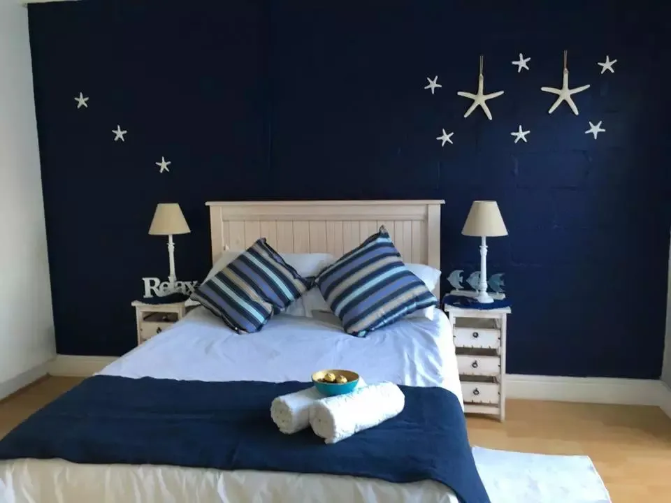 Bedroom with dark blue wall white bed and starfish decorations