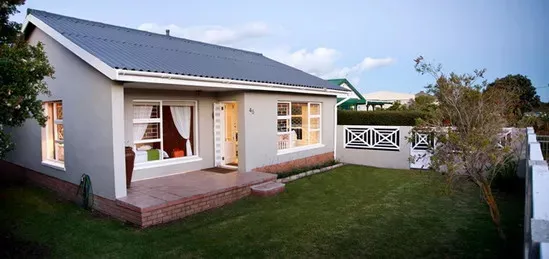 Singlestory house with a garden evening lighting and a white fence