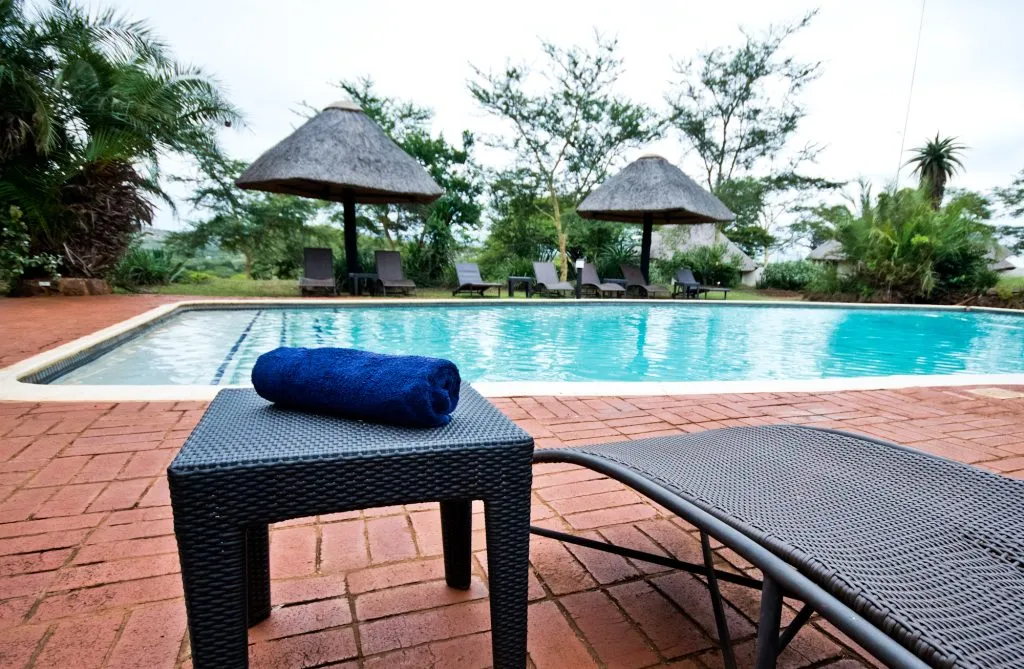 Swimming pool with lounge chairs umbrellas and a rolled towel on a table