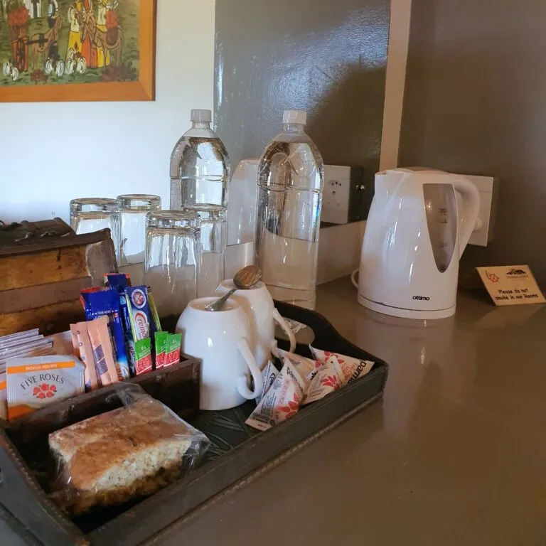 Tray with tea coffee biscuits kettle and water bottles on a counter