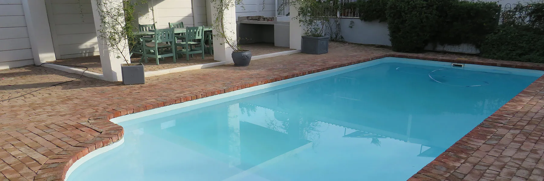Rectangular swimming pool with brick surround and outdoor seating area