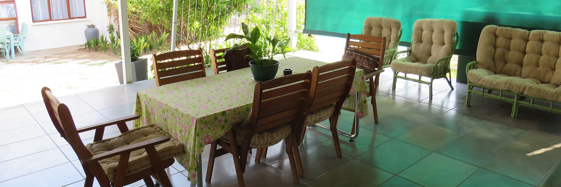 Outdoor patio with table chairs and sofas under a green shade