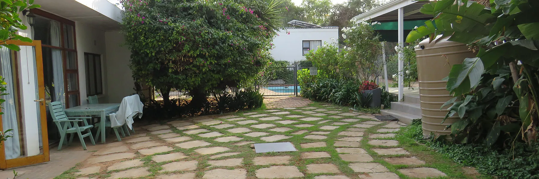Garden patio with stone path chairs and greenery leading to a pool