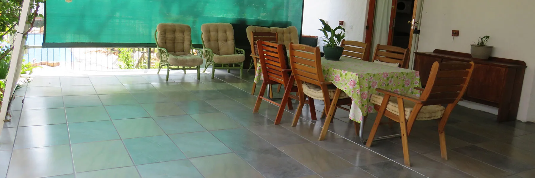 Dining area with table chairs and potted plants on a tiled floor