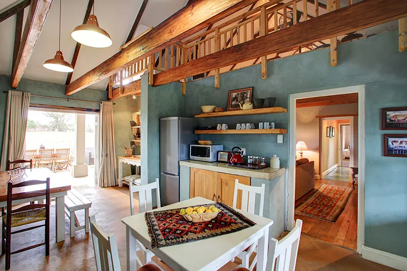 Cozy kitchen with wooden beams dining table and open doorway to living area