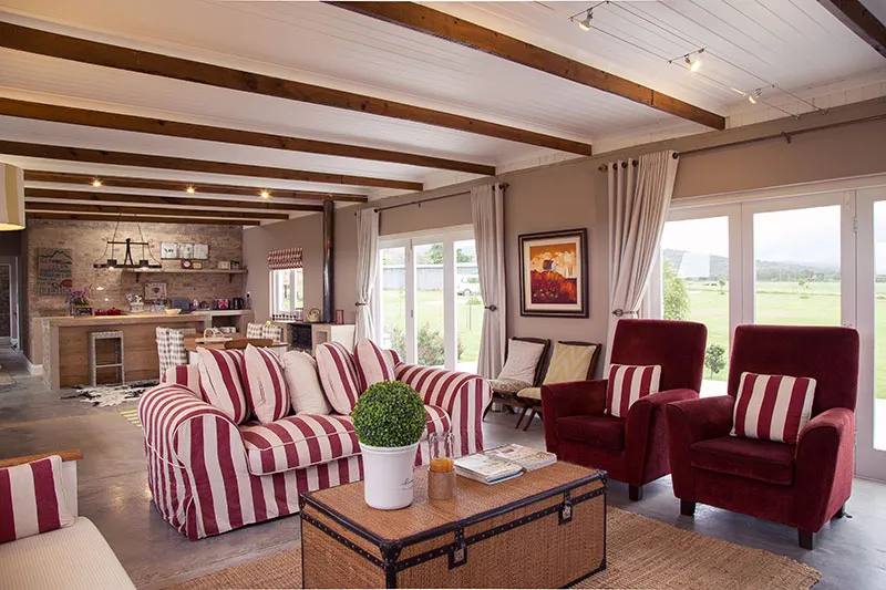Modern living room with striped sofa red armchairs and large windows