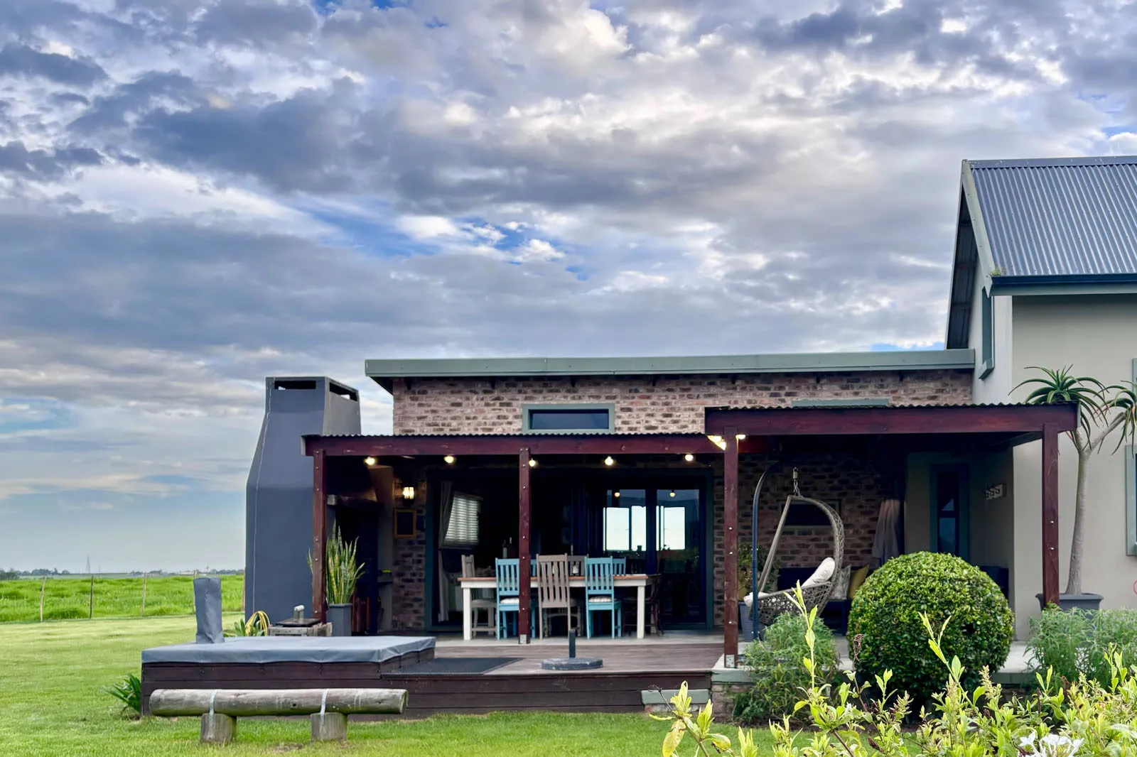 Modern house with covered patio outdoor seating and garden under a cloudy sky