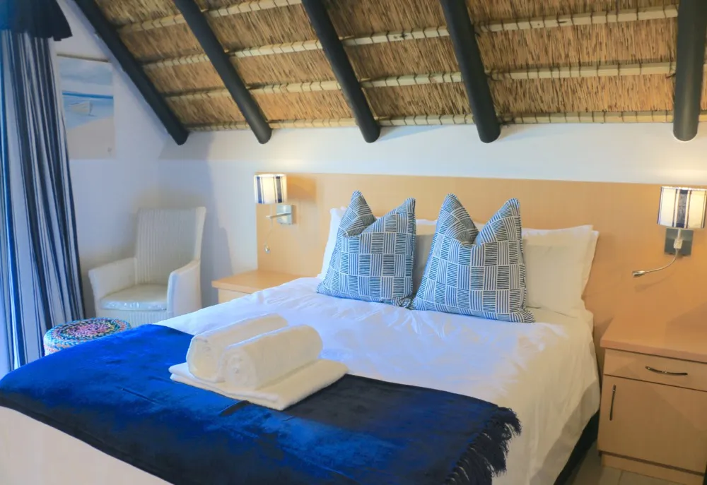 Cozy bedroom with a neatly made bed blue pillows and wooden ceiling