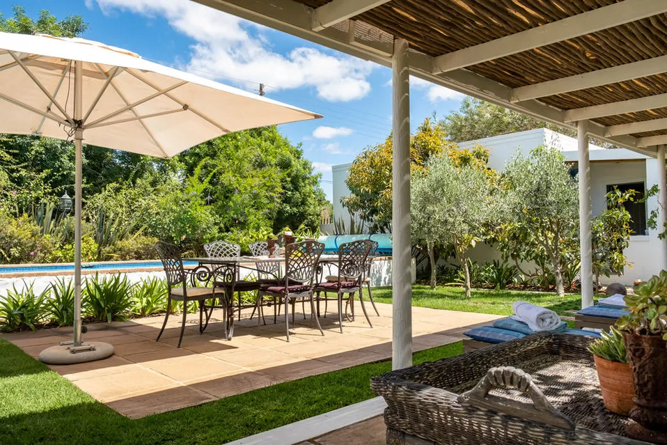 Patio with dining table chairs pool and garden under a pergola