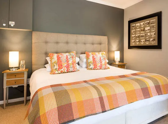 Cozy bedroom with a neatly made bed two lamps and framed pictures on the wall