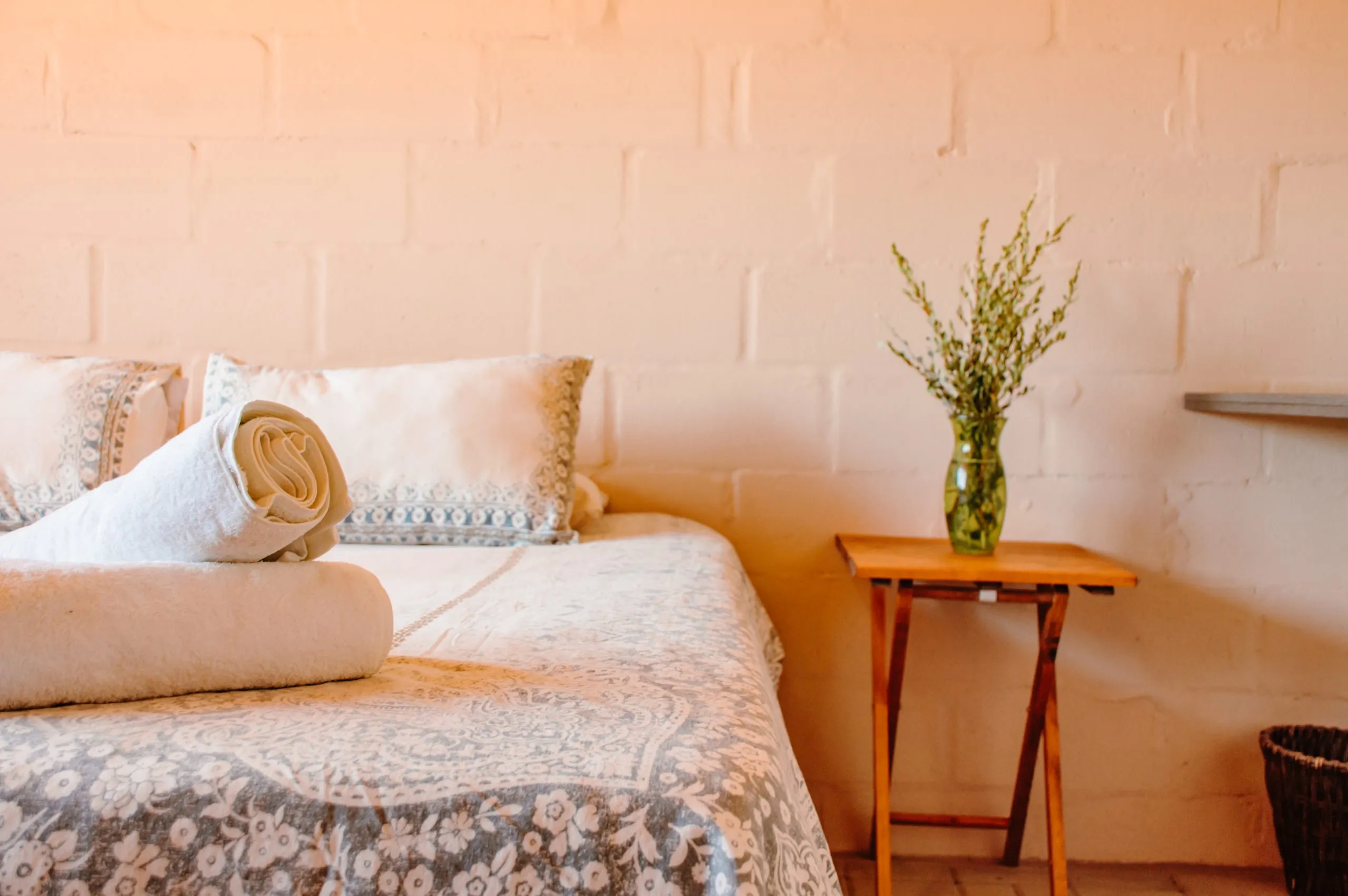 Rolled towel on bed floral bedding side table with plant in a room