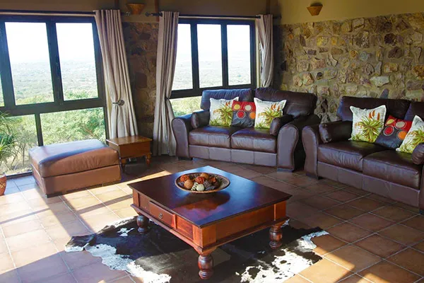 Cozy living room with sofas coffee table and large windows with stone walls