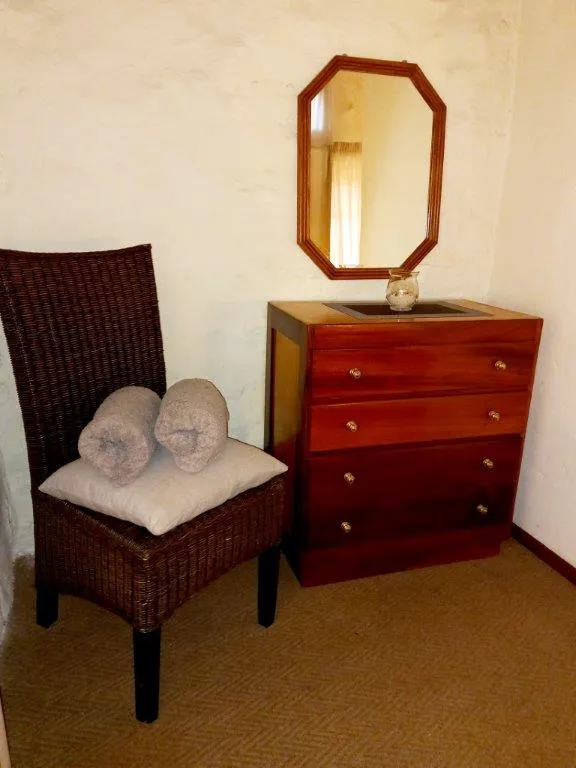 Wicker chair with towels and a wooden dresser with a mirror in a room