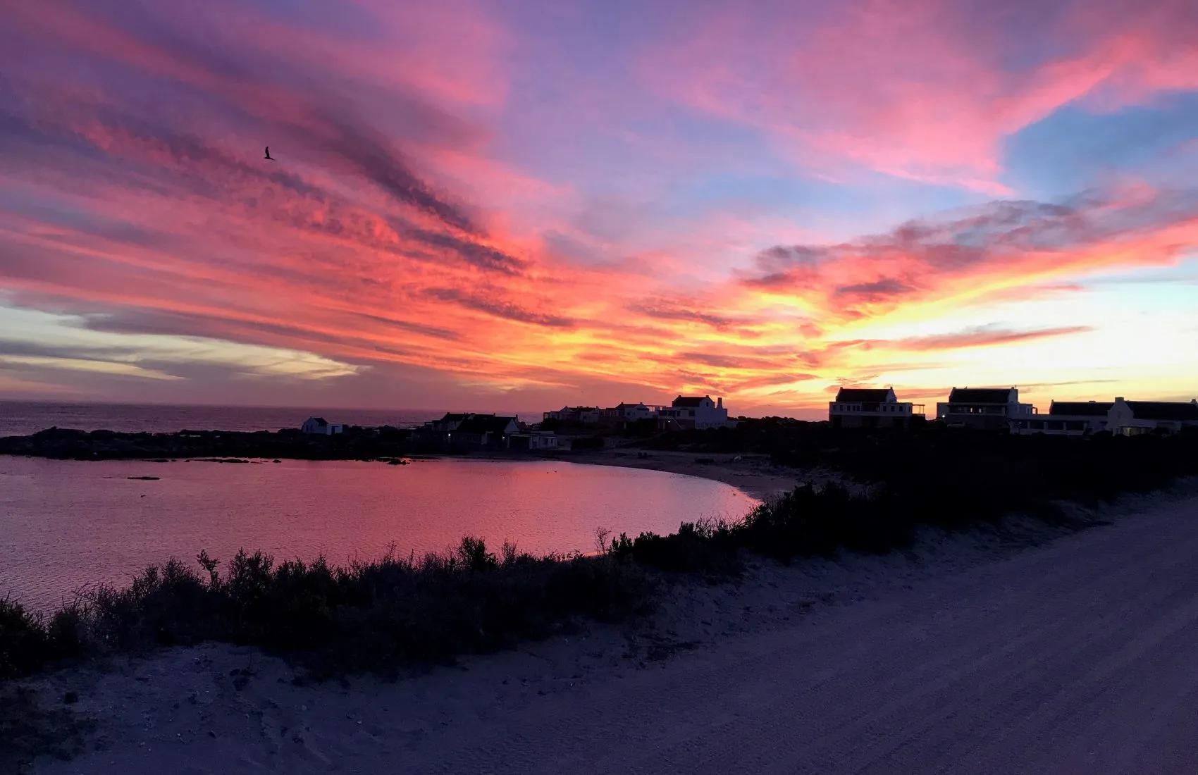 Sunset over a beach with colorful sky water and distant buildings