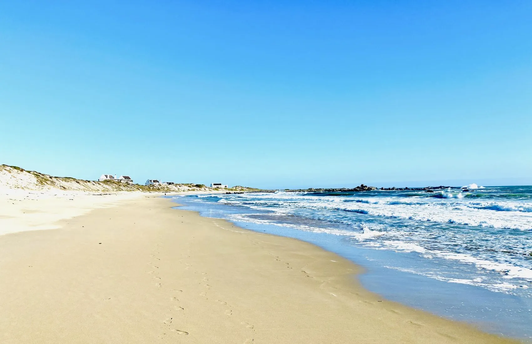 Sandy beach with gentle waves under a clear blue sky