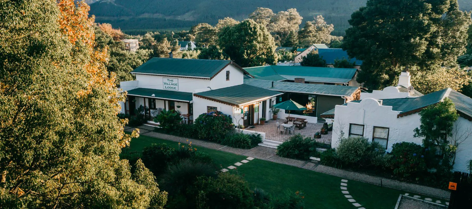White buildings with green roofs surrounded by trees and a garden