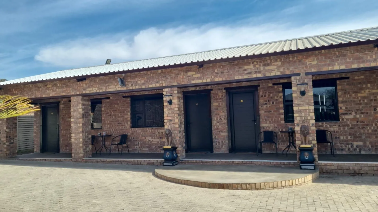 Brick building with three doors windows and outdoor seating under a blue sky