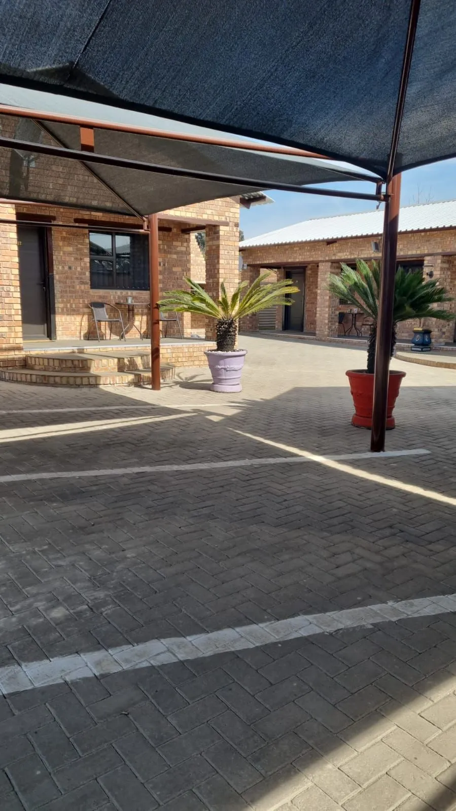 Brick house with potted plants under a shaded patio area