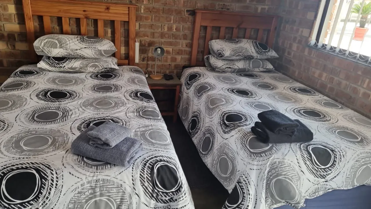 Two single beds with patterned bedding in a brickwalled room