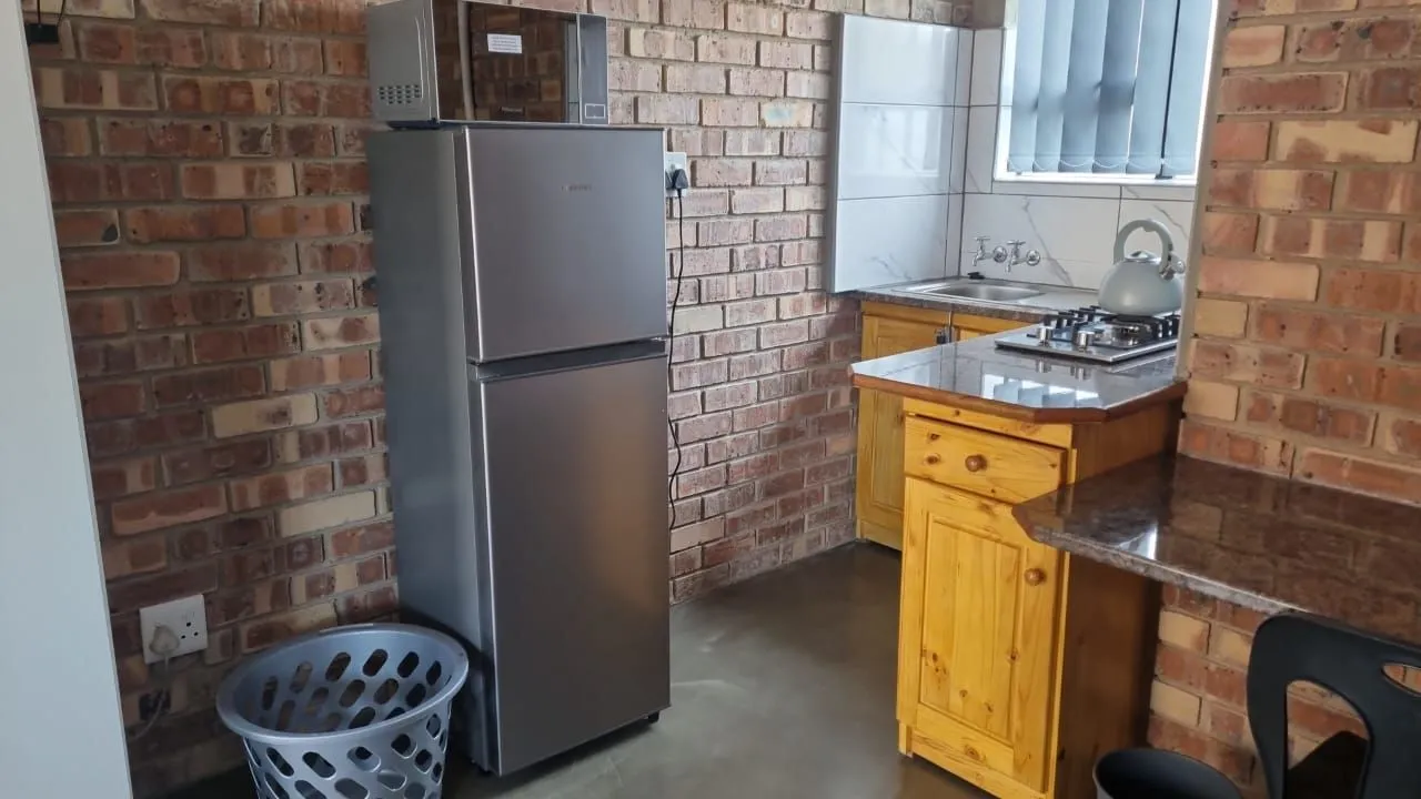 Kitchen with silver fridge brick wall wooden cabinets and countertop