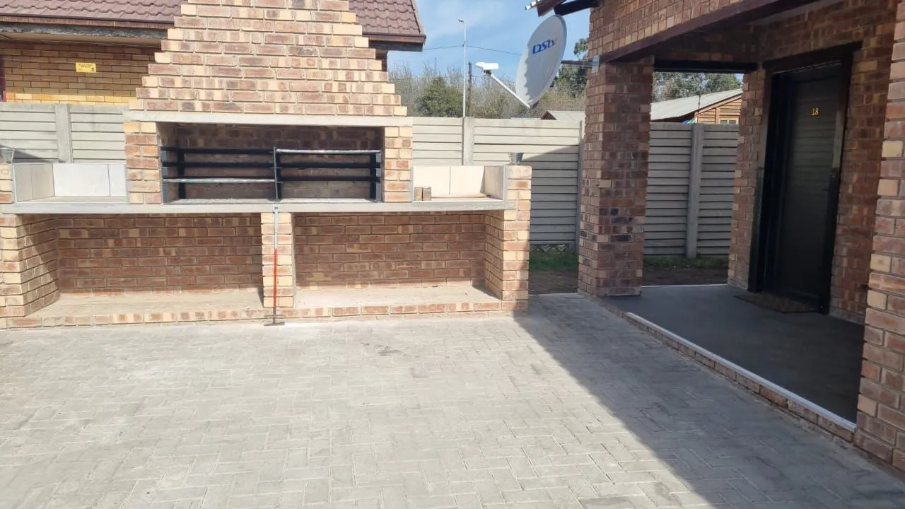 Outdoor brick barbecue area with paved ground and adjacent building entrance