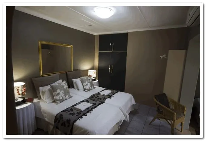 Bedroom with two single beds lamps and a wicker chair