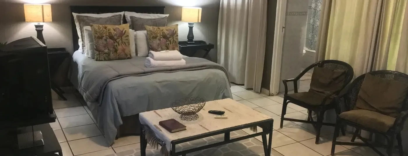 Bedroom with a bed two chairs a coffee table and curtains