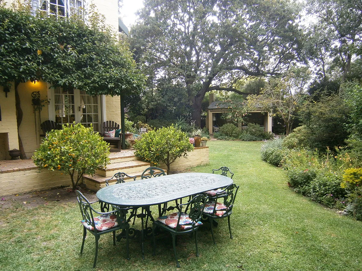 Garden with a metal table and chairs on a lawn near a house