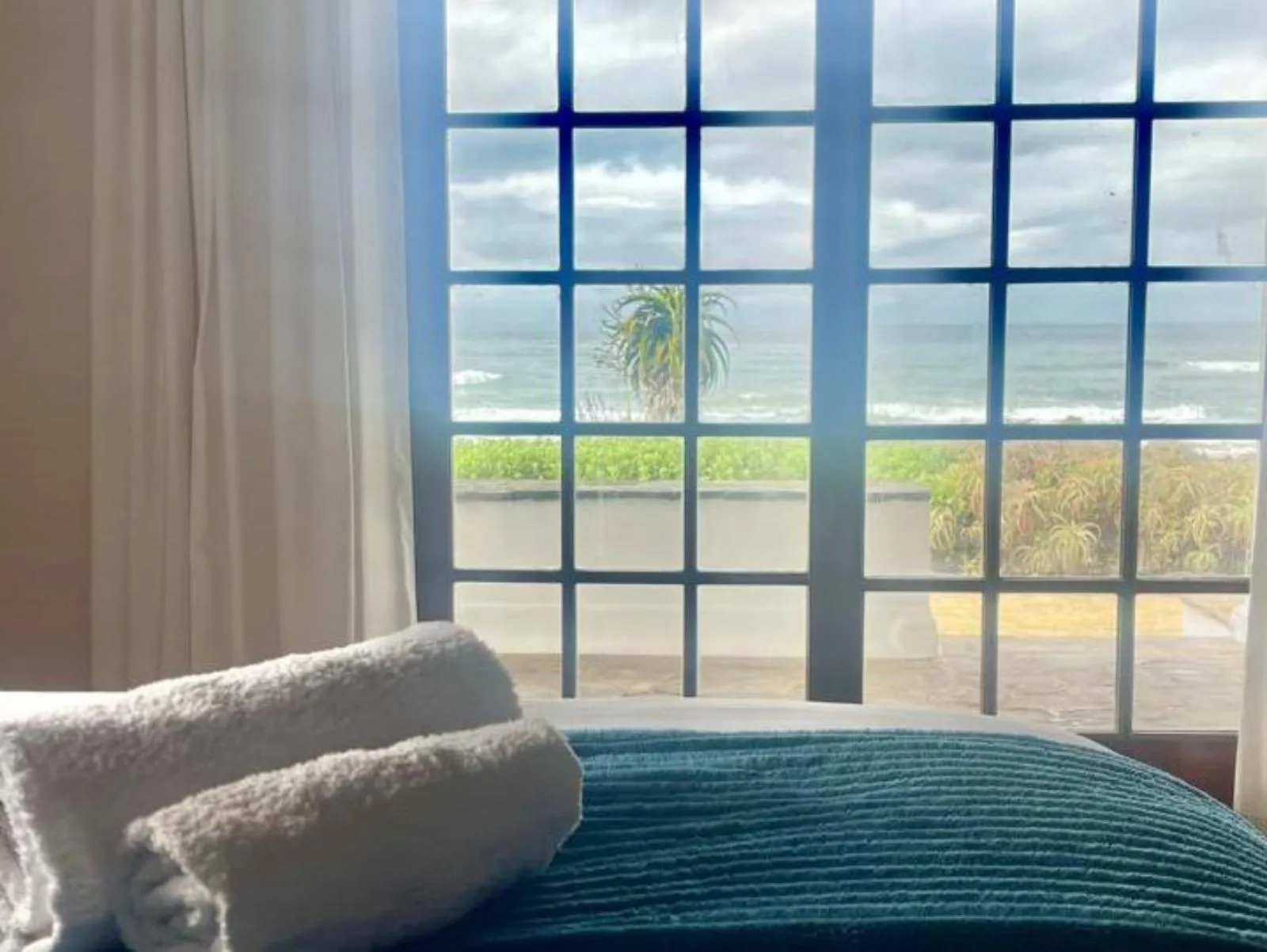 Towels on a bed with a view of the ocean through a window