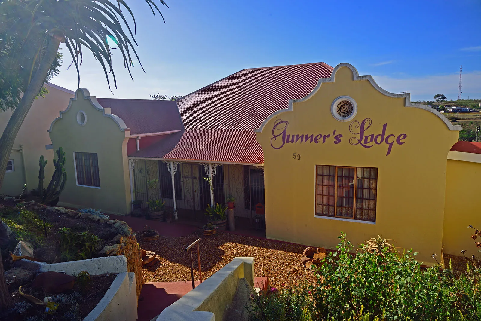 Yellow building with Gunners Lodge sign red roof and garden area
