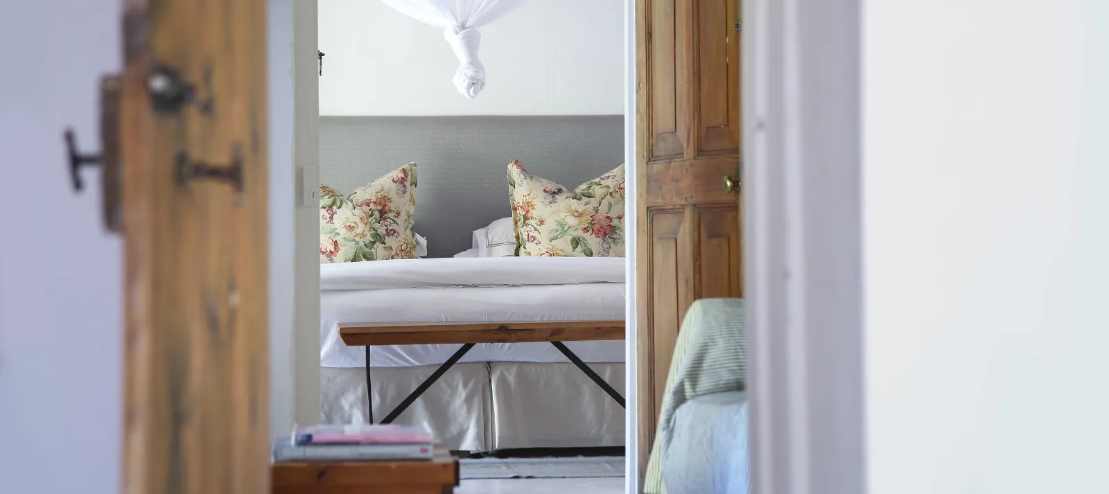 View of a cozy bedroom with floral pillows and wooden doors framing the scene