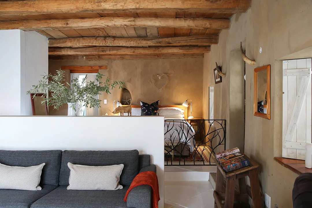 Cozy living room with sofa wooden ceiling and view into bedroom area
