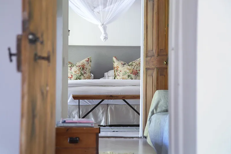 Wooden bed with floral pillows framed by open doors in a cozy bedroom