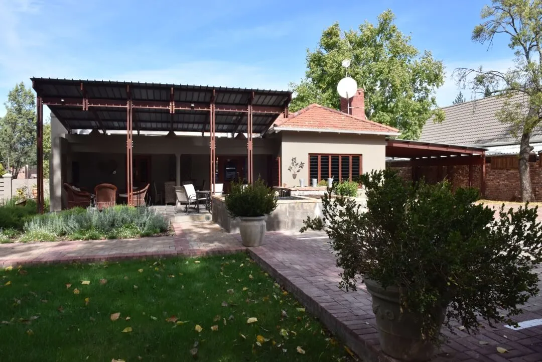 House with a patio garden and potted plants in a sunny yard