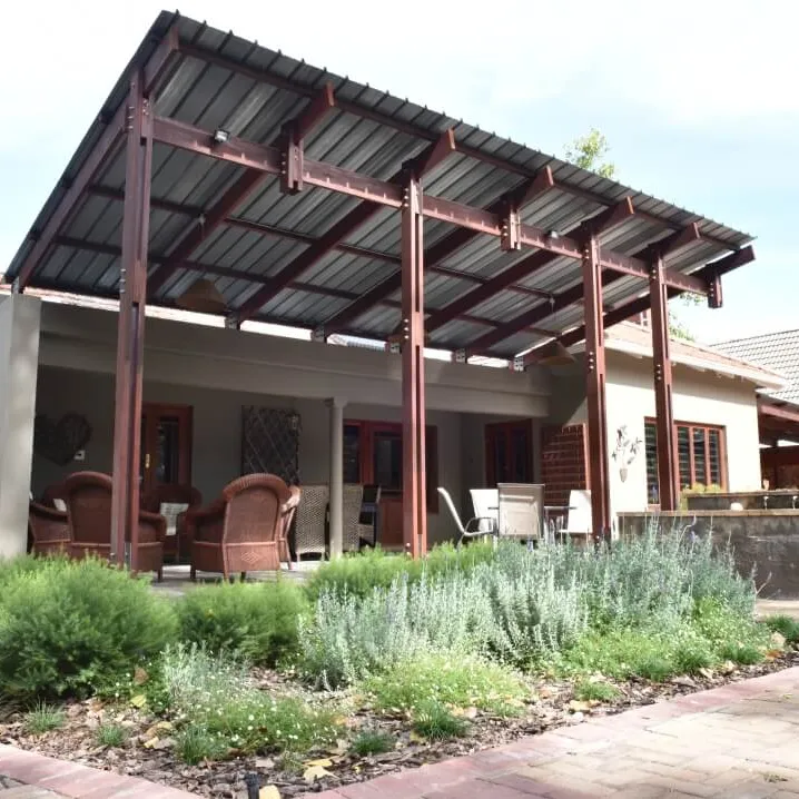 Patio with wooden chairs and table surrounded by greenery