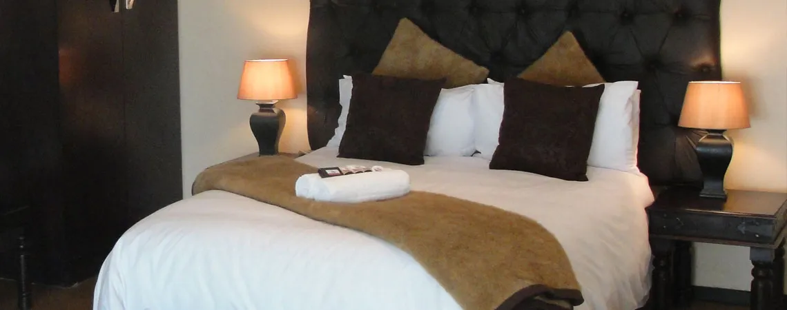 Cozy bedroom with a neatly made bed two bedside lamps and brown pillows