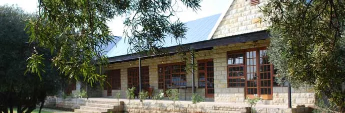 Stone house with blue roof surrounded by trees and greenery