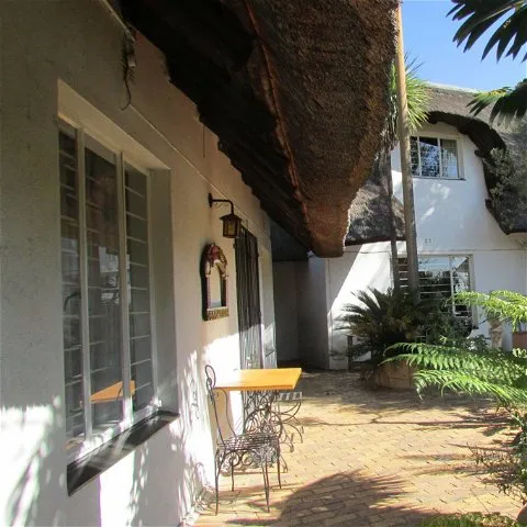 Thatchedroof house with outdoor seating area and lush greenery