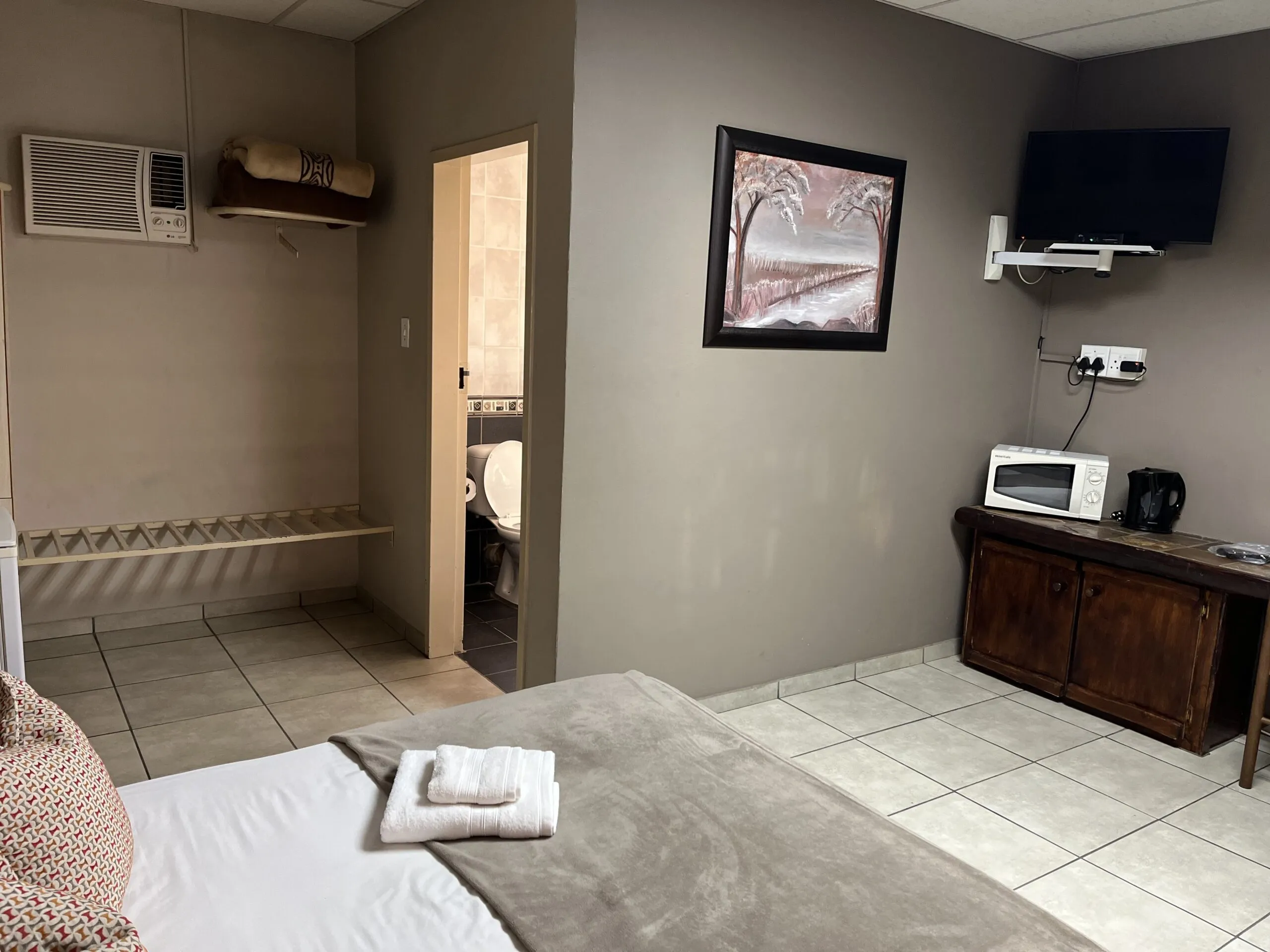 Bedroom with bed TV microwave and adjacent bathroom