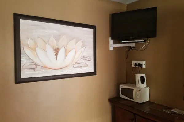 Framed lotus painting on wall with TV microwave and power outlets