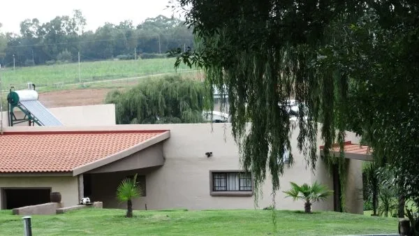 House with redtiled roof and green lawn trees in the background